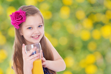 girl with a red bow and a glass of orange juice.healthy food concept,active lifestyle,happiness concept,carefree childhood concept.の写真素材
