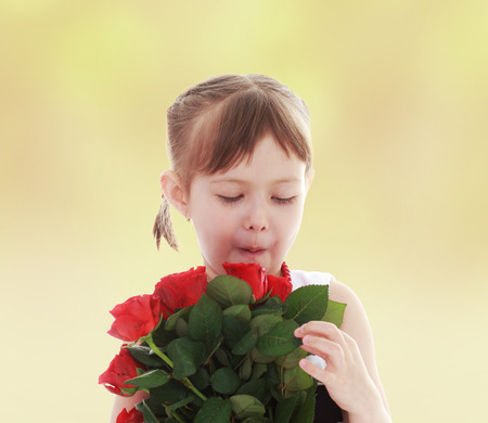 Girl considers a bouquet of roses happy childhood, carefree childhood concept の写真素材