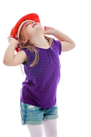 Curious little girl in the construction helmet.Happy childhood, fashion, autumnal mood concept. Isolated on white backgroundの写真素材