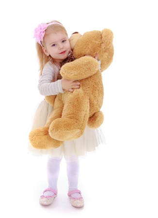 Cheerful little girl hugging a teddy bear. Studio photo, isolated on white background.の写真素材