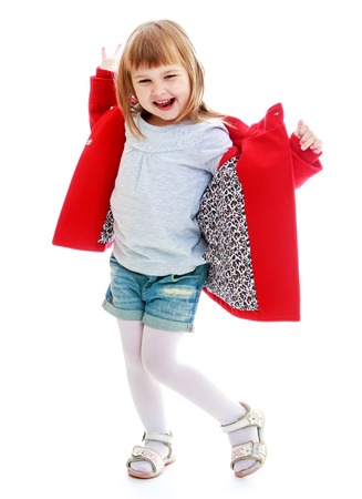 Laughing little girl in red coat in short shorts.Isolated on white background.の写真素材