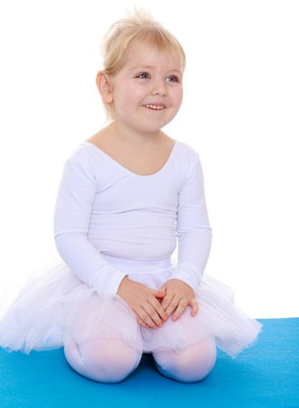 Portrait of a beautiful little girl sitting on the sports mats .. Isolated on white.の写真素材