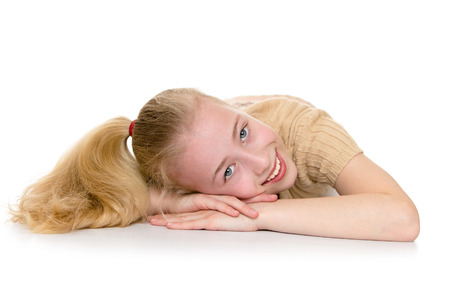Charming blond girl with a long tail on the head, cute smiling at the camera while lying on the floor - isolated on white.の写真素材