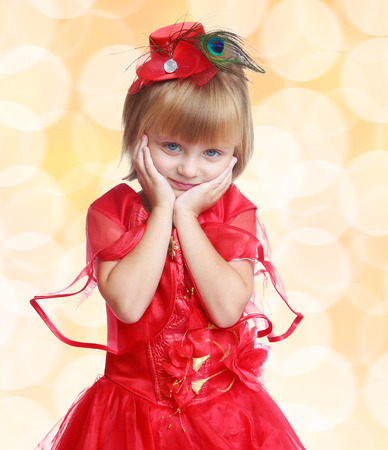 Stylish little girl in a red dress, close-up, pale yellow backgroundの写真素材