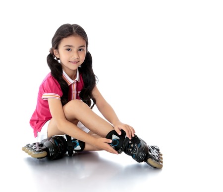 Charming dark-haired girl of preschool age in short white shorts and a pink t-shirt sitting on the...