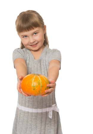 Cute little blond girl with short bangs on her head, holding in his outstretched hands a pumpkin. The plan - Isolated on white backgroundの写真素材