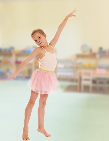 Charming little girl ballerina in a pink translucent dress.Against the background of a child's room .の写真素材