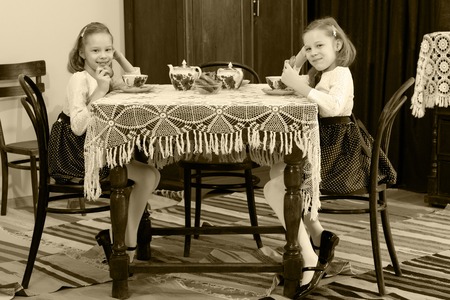 Girls Twins drinking tea at an antique table with a lace tableclの写真素材