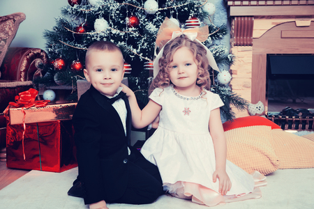 Boy and girl with gifts near the Christmas tree.の写真素材
