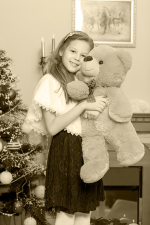 little girl with a Teddy bear near the fireplace.の写真素材