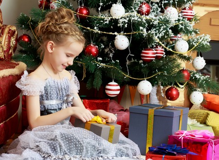 little girl with a gift near the Christmas tree.の写真素材