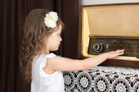 Little girl listens to old radio.の写真素材