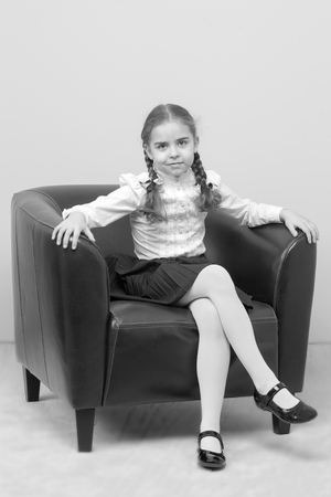 A little girl is sitting on a chair.の写真素材