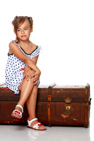 A little girl is sitting on a wooden box.の写真素材