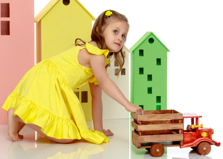Little girl is playing with a wooden car.の写真素材