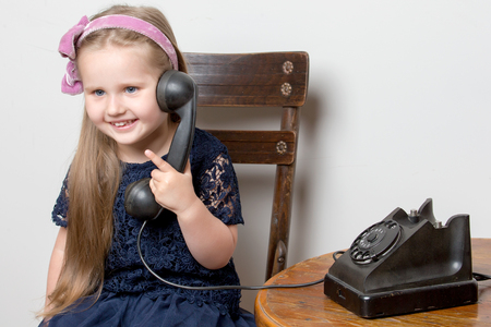 A little girl is ringing on the old phone.の写真素材