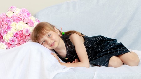 Little girl on the couch with a bouquet of flowersの写真素材