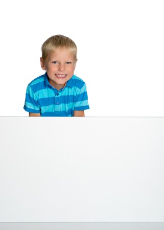 A little boy is looking from behind an empty banner.の写真素材