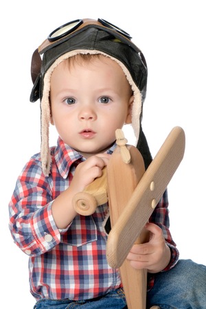 A little boy in a pilots cap and a wooden plane in his handの写真素材