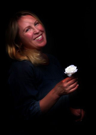 Portrait of a young woman with a white rose in her handの写真素材