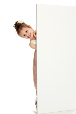 A little girl peeks out from behind the banner.の写真素材