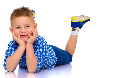 Happy little boy is lying on the floor in the studio.の写真素材