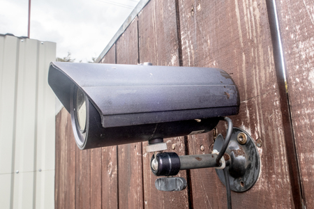 An old CCTV camera on a wooden fence.の写真素材