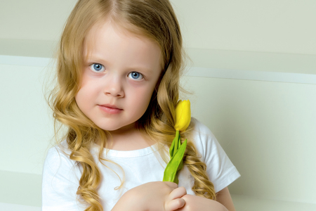 A little girl with a bouquet of tulips is sitting on the stairs.の写真素材