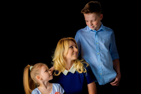 Happy young mother with her son and daughter on a black backgrouの写真素材