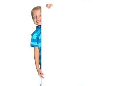 A little boy is looking from behind an empty banner.の写真素材
