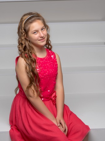 A teenage girl is sitting on a white staircase.の写真素材
