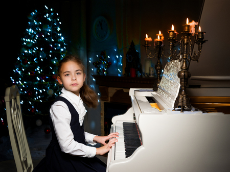 Little girl plays the piano by candlelight.の写真素材