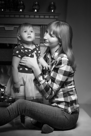 A young mother with her daughter by the fireplace.の写真素材