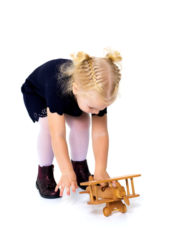 Little girl is playing with a wooden plane.の写真素材