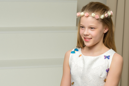 Beautiful little girl is sitting on the white staircase.の写真素材