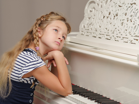 The girl is at the white grand piano.の写真素材
