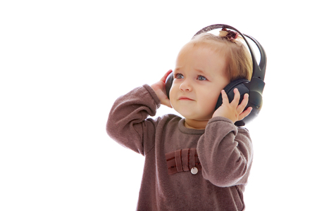 A little girl with headphones listening to music.の写真素材