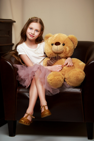 Little girl on sofa hugging teddy bear.の写真素材