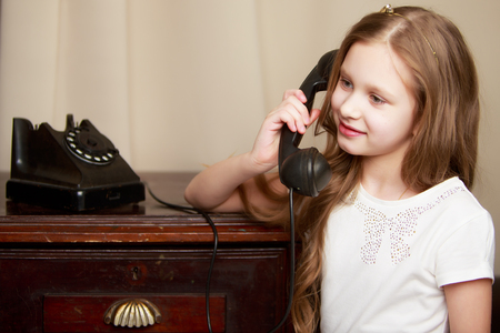 A little girl is ringing on the old phone.の写真素材