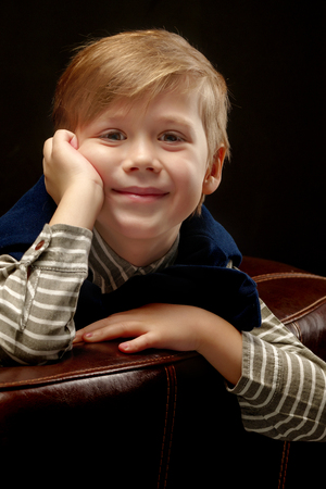 Beautiful little boy on a black background, close-up.の写真素材