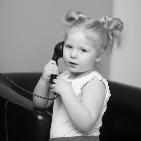 A little girl is ringing on the old phone.の写真素材