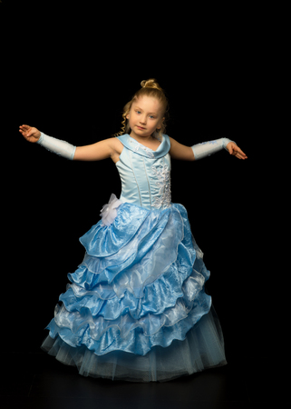 A little girl in a long, elegant dress of a princess on a blackの写真素材