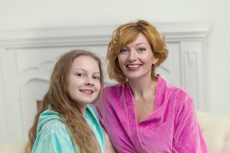 Daughter and mother in bathrobes posing in the studio. The conceの写真素材
