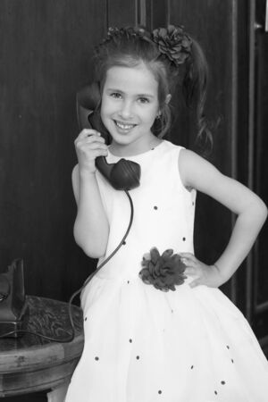 A little girl is ringing on the old phone.の写真素材