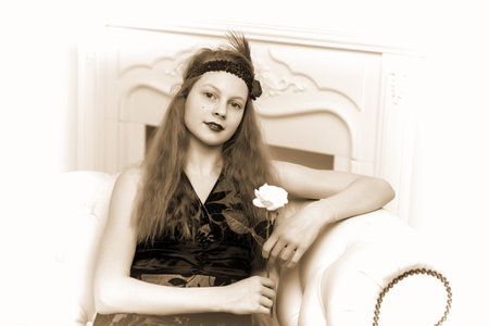 Teen girl sitting on the couch holding a flower in her hand.