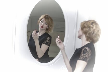 Young woman uses mascara near the mirror. Beauty and care. Studiの写真素材