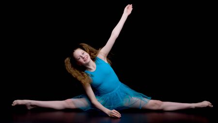 Girl gymnast in the studio on a black background performs gymnasの写真素材