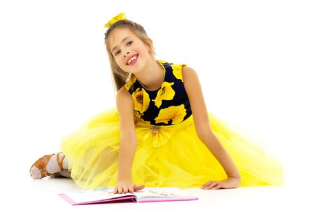 A schoolgirl girl is sitting on the floor surrounded by books.の写真素材