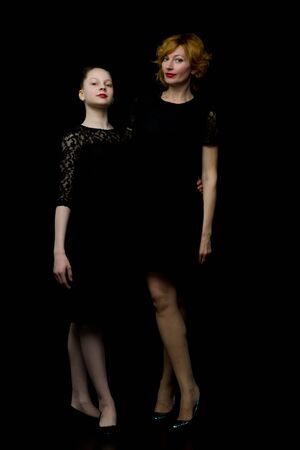 Mom and little daughter studio portrait.On black backgroundの写真素材