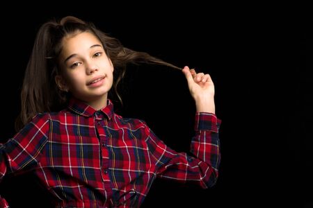 A beautiful little girl straightens her hair on her head.の写真素材